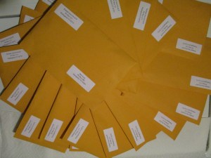 A spiral-shaped pile of manila envelopes with NAACP return addresses. The top envelope is addressed to Governor Phil Scott.