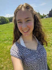 Ari Graham-Gurland, outside in a meadow, smiling at the camera.
